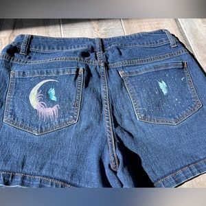 Repurposed denim shorts with hand painted details on the pockets.